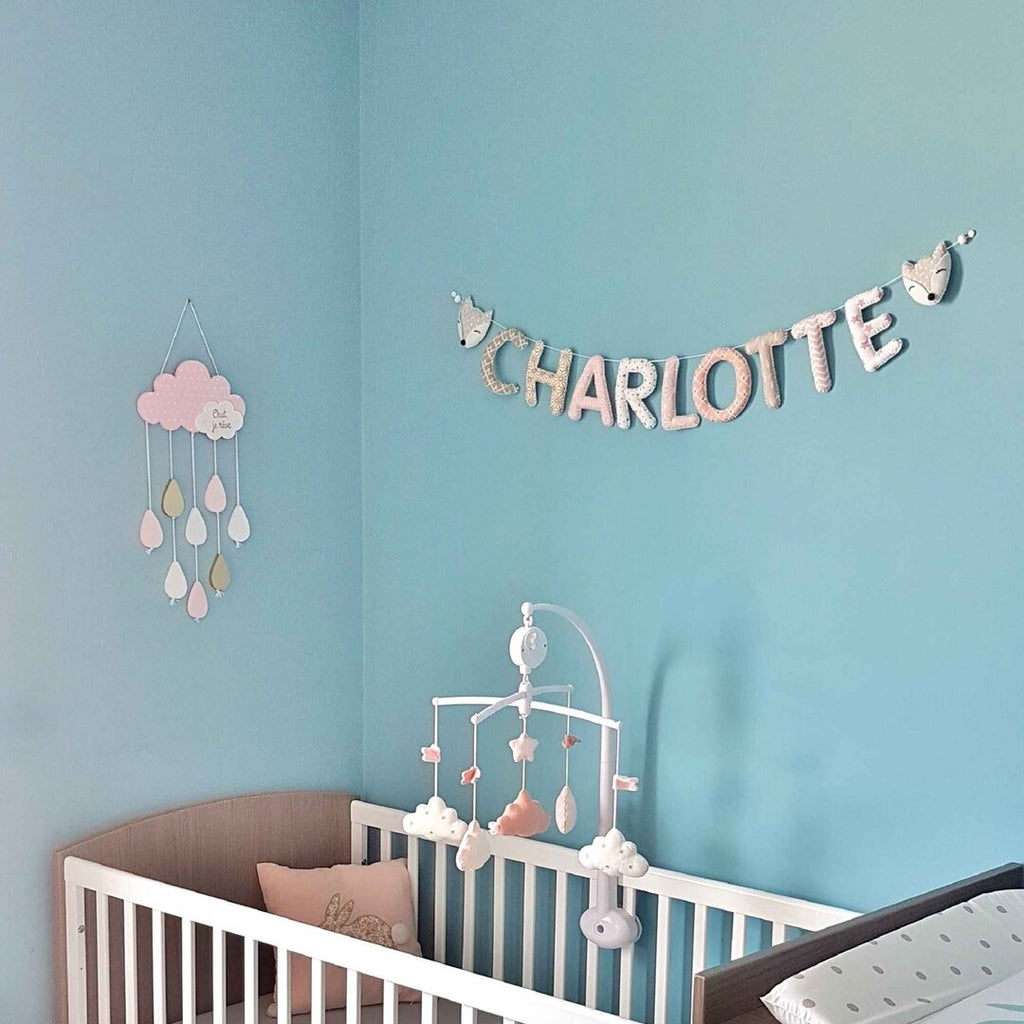 Guirlande prénom en tissu pastel avec embouts renard, exemple « Charlotte », sur un mur bleu canard de chambre de bébé fille