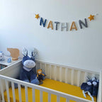 Guirlande prénom en tissu bleu marine et jaune moutarde avec étoiles, exemple « Nathan », dans une chambre de bébé garçon
