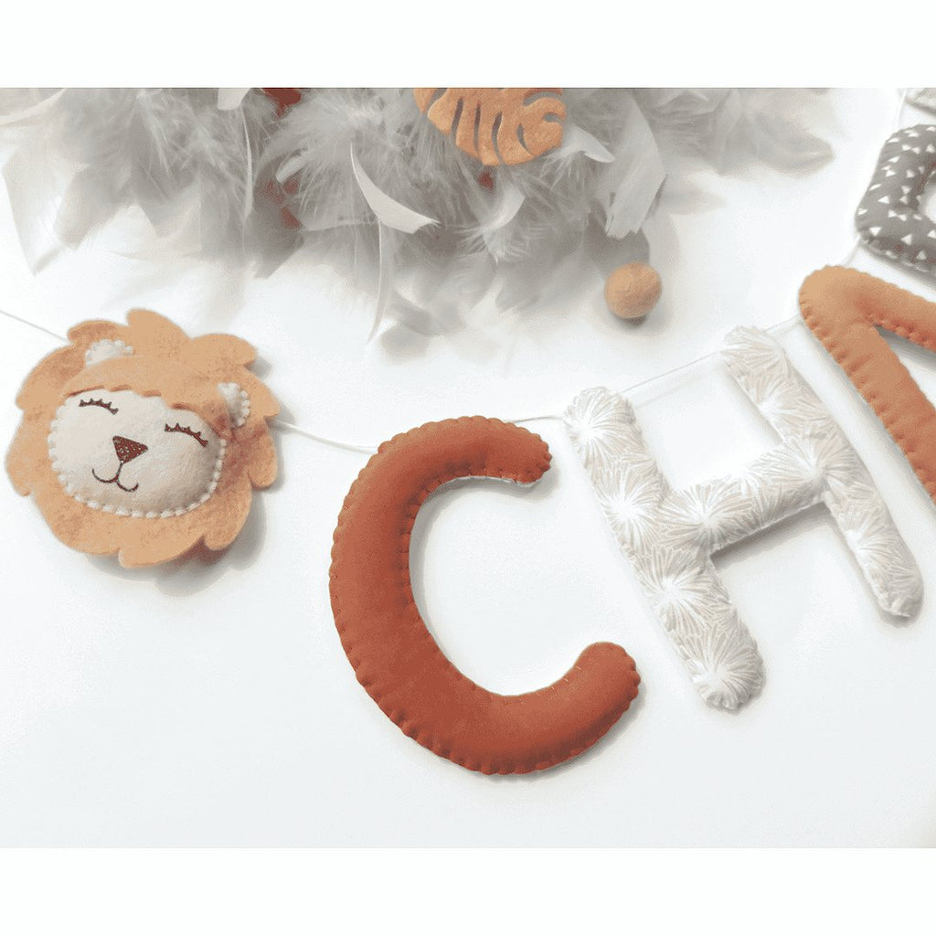 Guirlande prénom personnalisée accrochée dans une chambre d'enfant jungle, motif lion beige