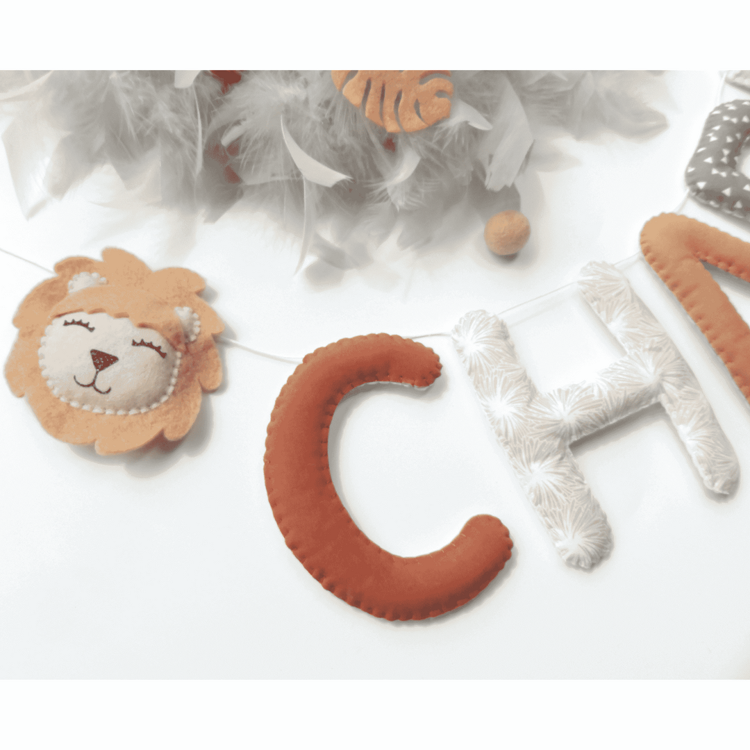 Guirlande prénom personnalisée accrochée dans une chambre d'enfant jungle, motif lion beige
